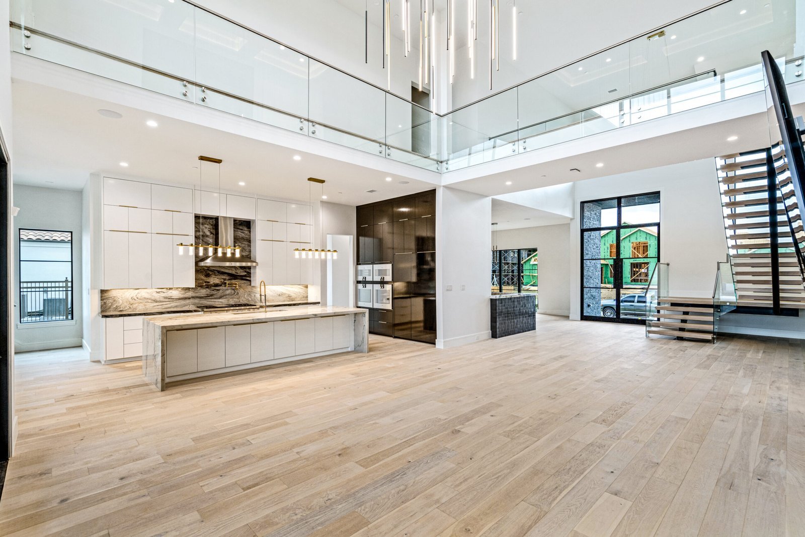 Open kitchen and living area with floating staircase at Balfour Court Custom Home
