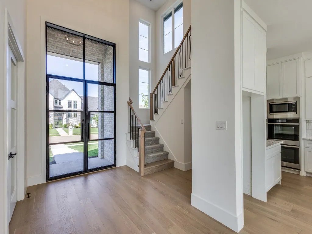 Bright two-story entry with a steel and glass front door and staircase