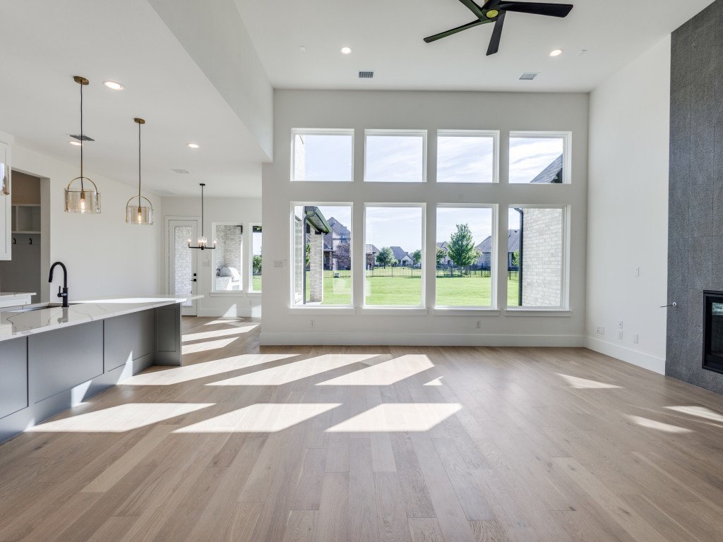 Open great room with tall windows, fireplace and adjoining custom kitchen