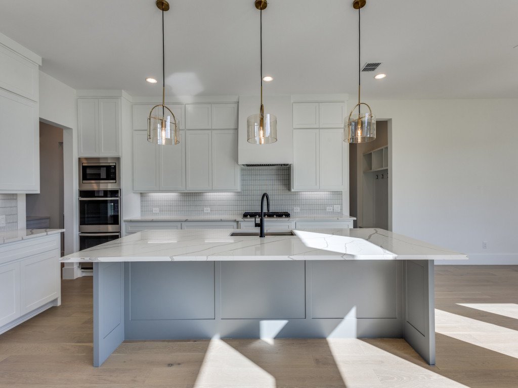 Large kitchen island with quartz counters and glass pendant lights