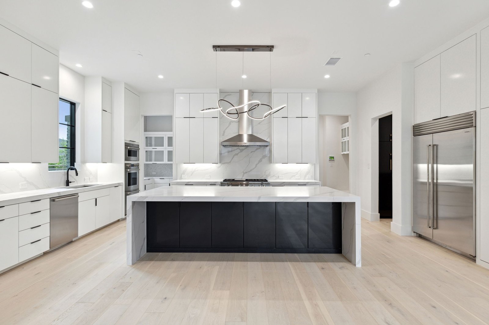 Custom white kitchen with contrasting island at Chambord Custom Home I