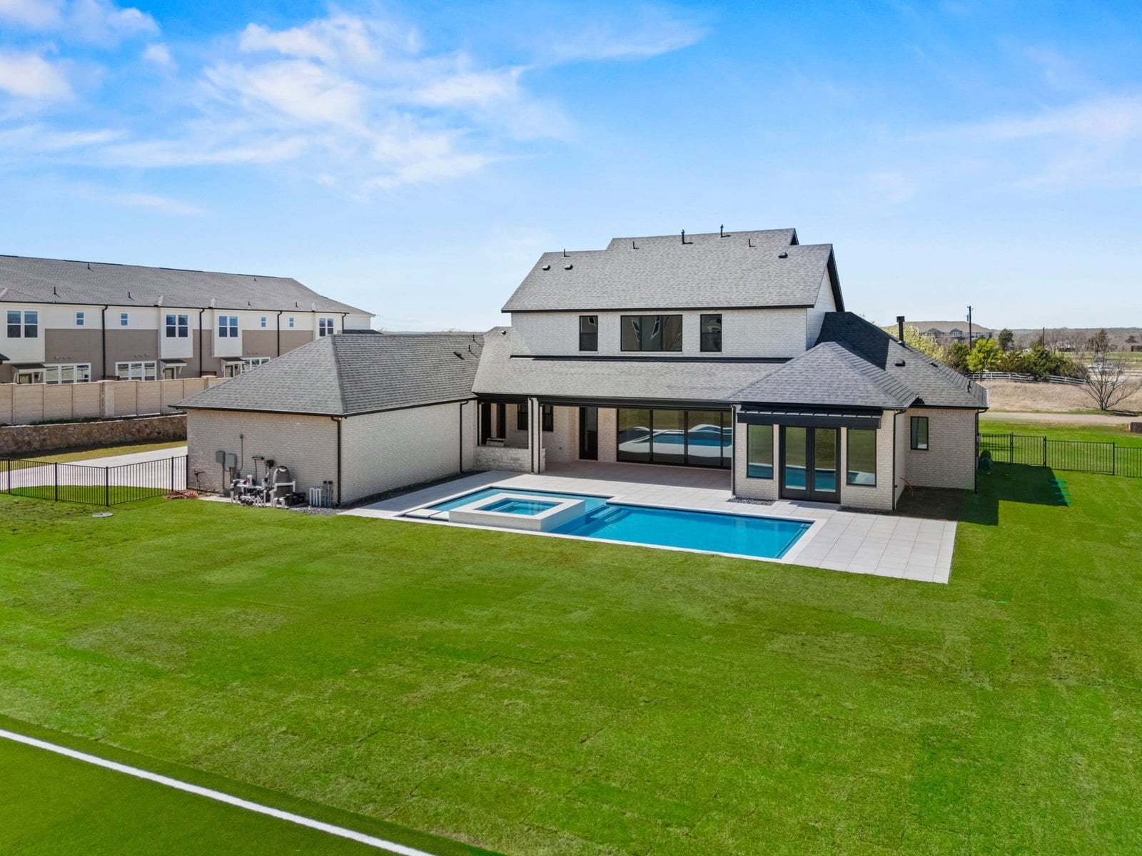 Aerial rear view of a Country Ridge custom home with a swimming pool and covered outdoor living area