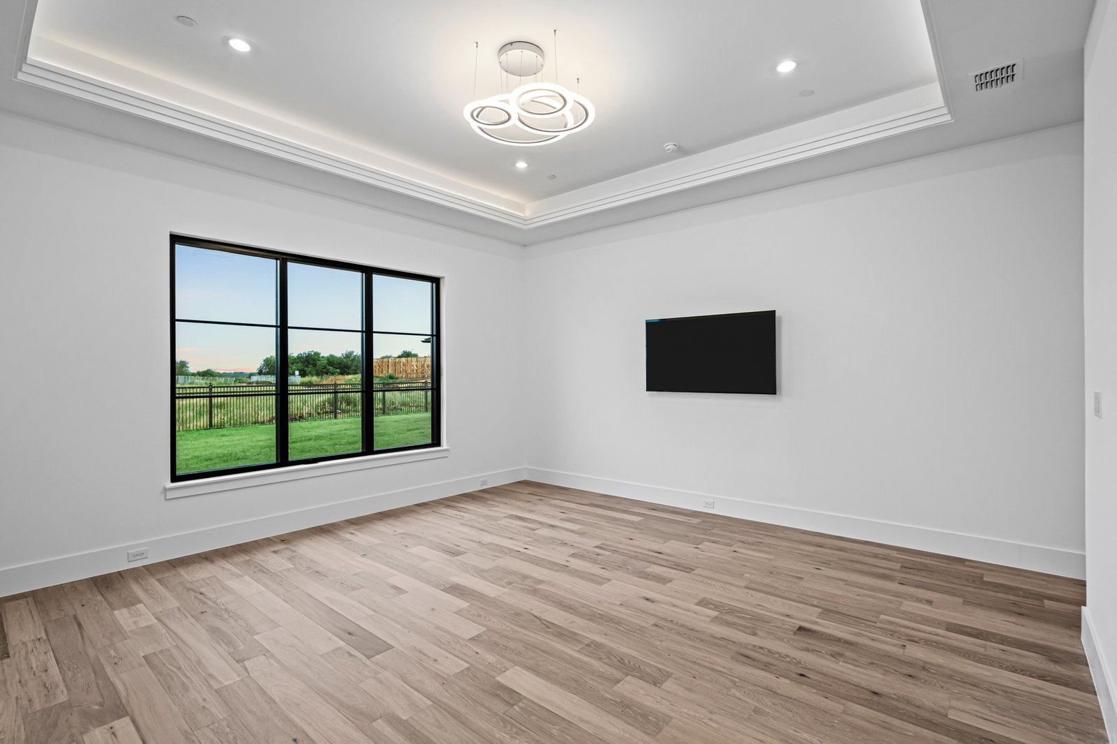 Light-filled bedroom with wide-plank wood flooring at Midwick Custom Home