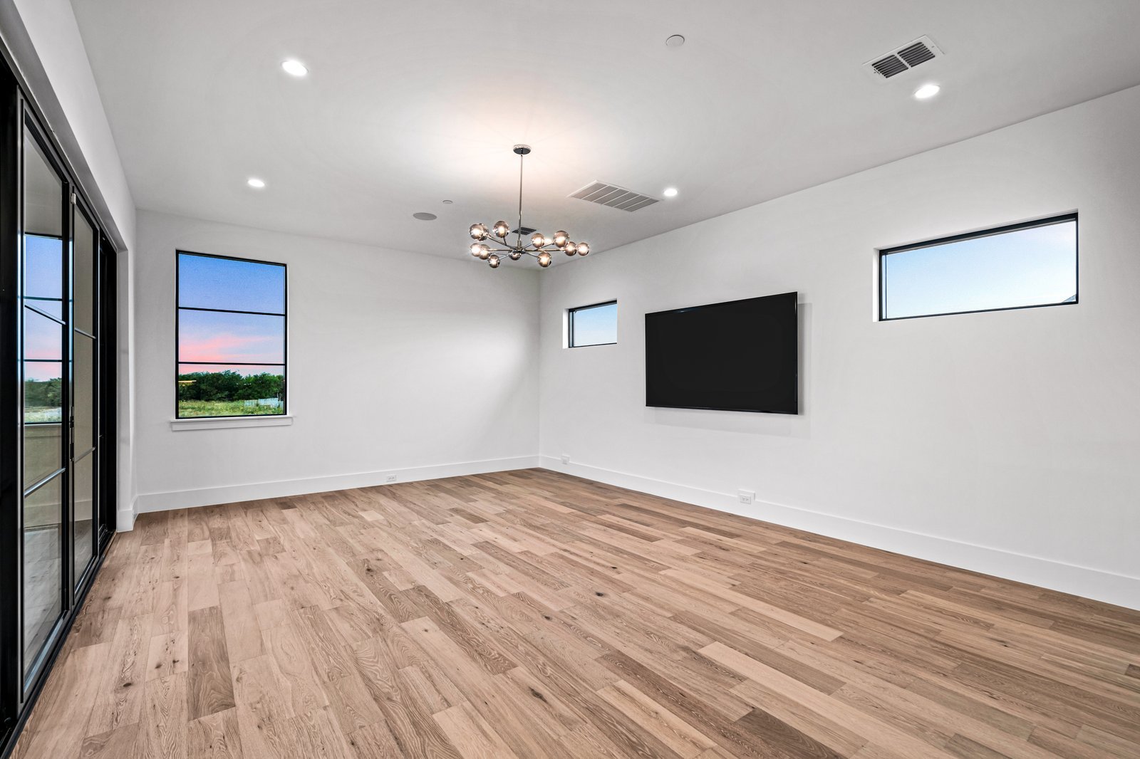 Media room with wide-plank wood flooring at Midwick Custom Home