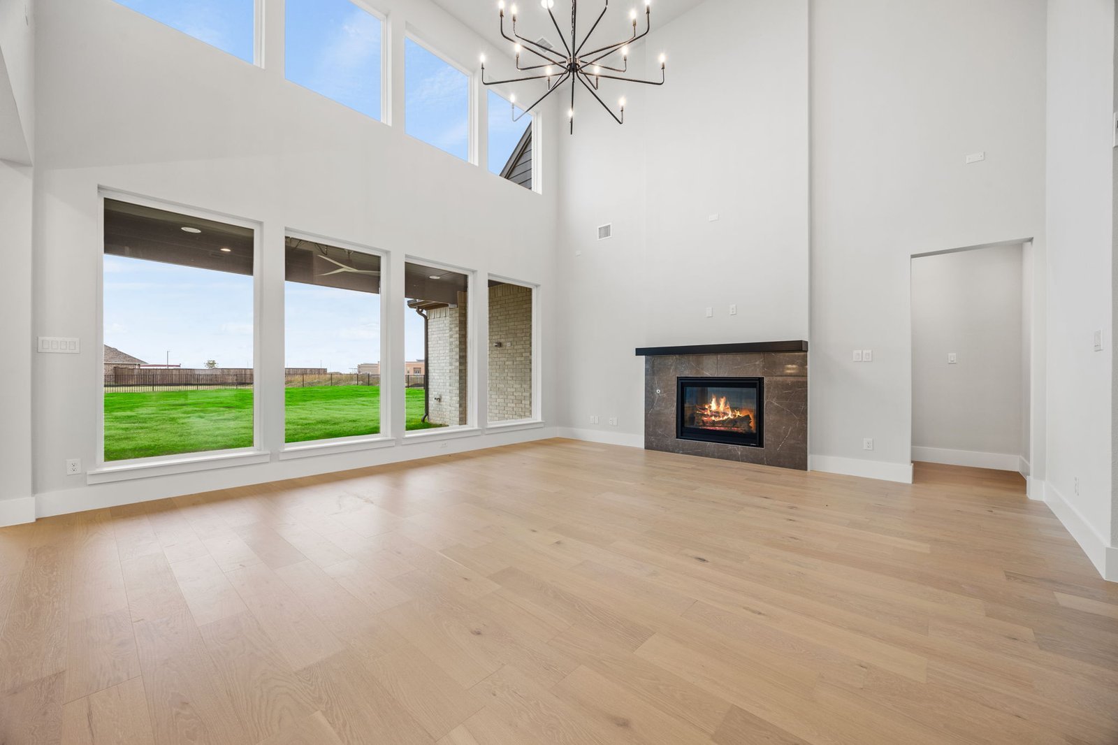Two-story great room with large windows and a modern fireplace in a Gunter custom home