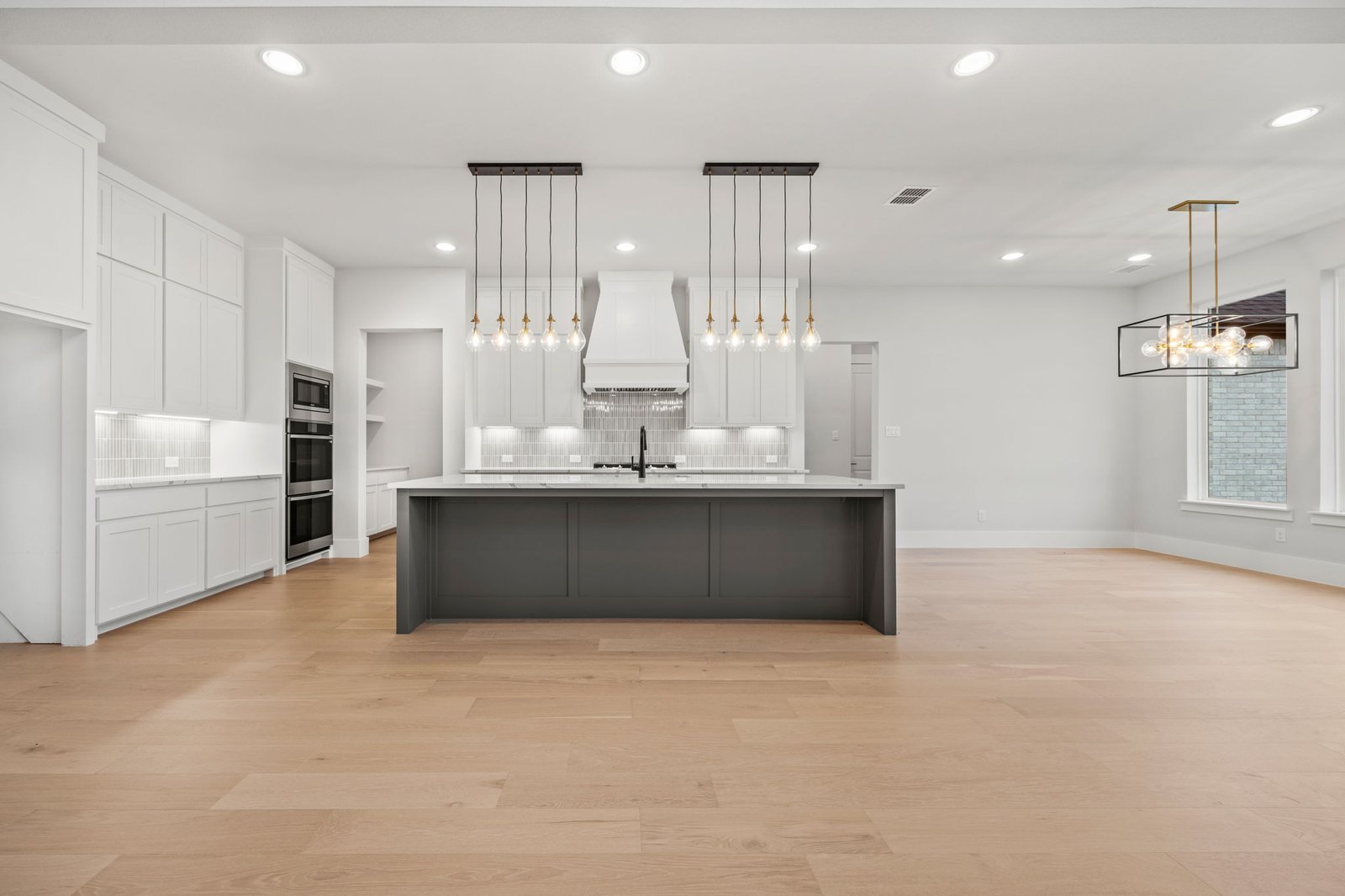 Custom white kitchen with a large dark island and designer pendant lighting