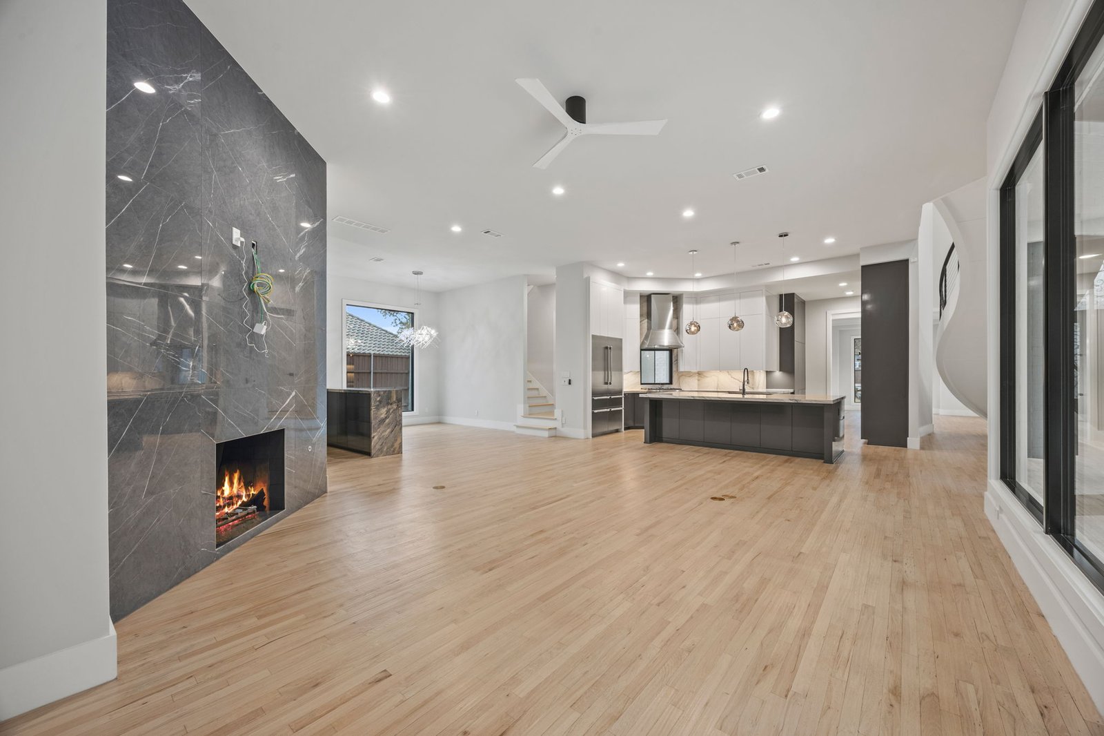 Open-concept kitchen and living area with a dark stone fireplace wall in the West Plano remodel