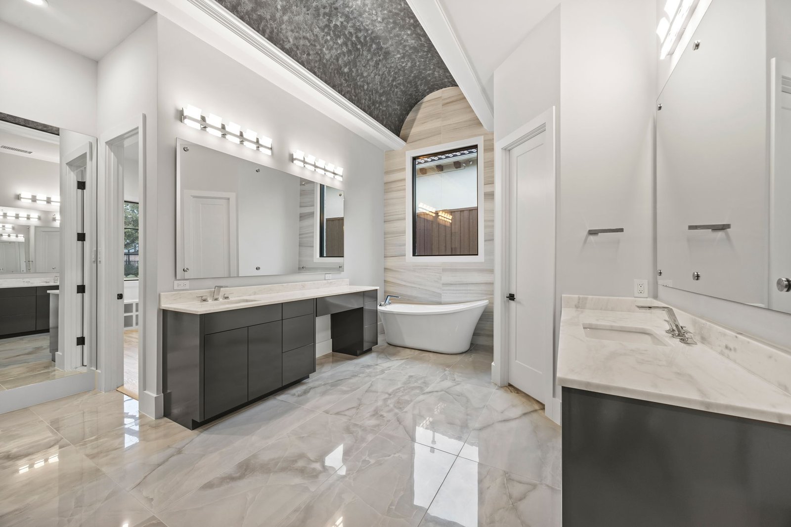 Renovated primary bathroom with a double vanity, freestanding tub and barrel-vaulted ceiling in West Plano