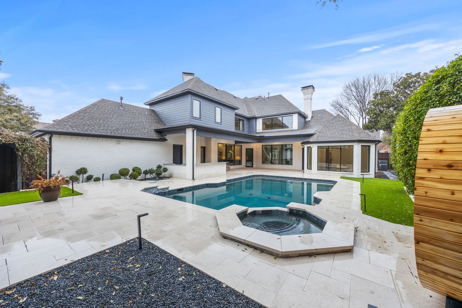 Completed rear exterior and outdoor living area with a pool, spa and stone patio in West Plano